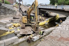 June 2021 - Workers place blocks for stream diversion in the Stony Creek in preparation for building the abutments for the new southbound bridge.